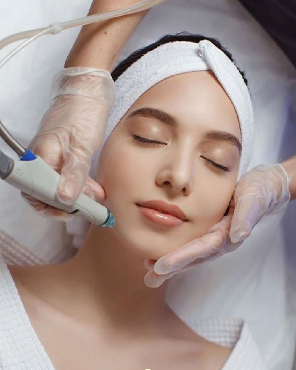 A hydra facial in progress, the therapist working a treatment wand across the cheek.