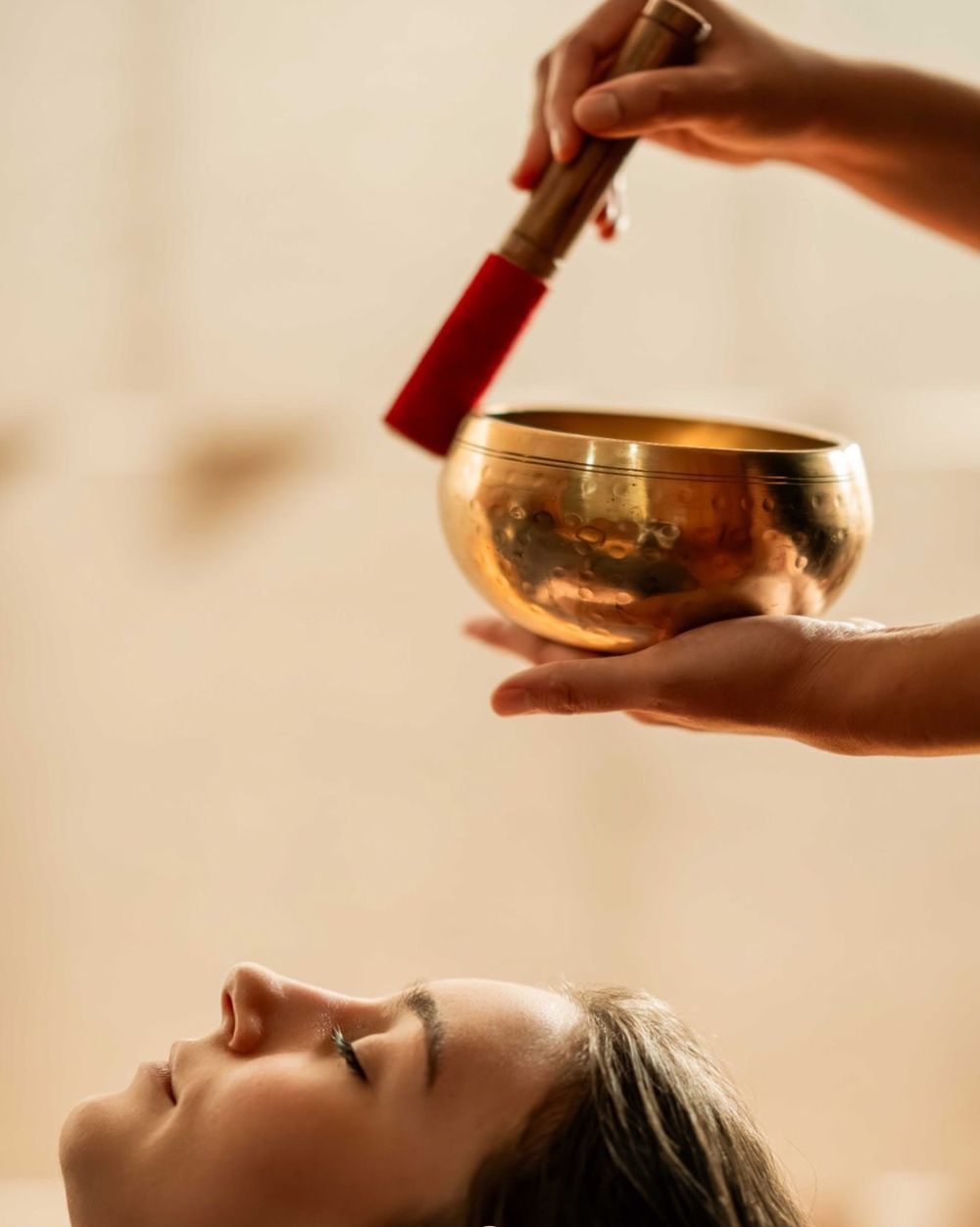 A singing bowl held above a guest during sound therapy.
